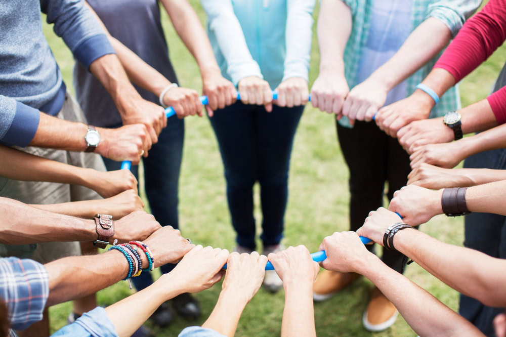 A team forming a circle while holding a hoop 