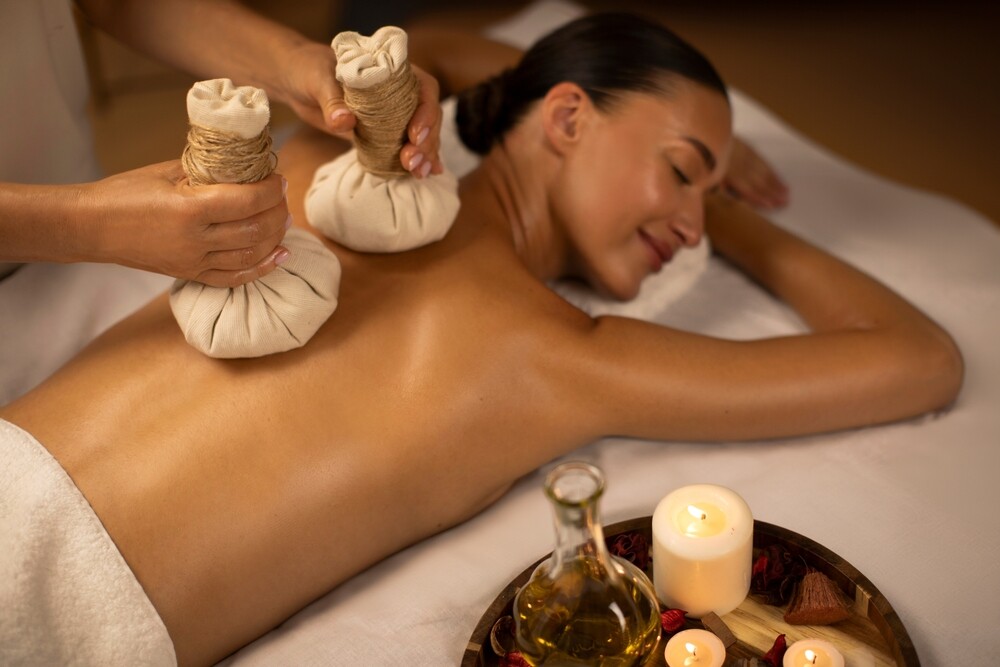 A woman experiencing a Thai herbal compress massage. 