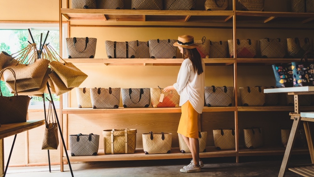 A woman looking at hand-woven bags in a store